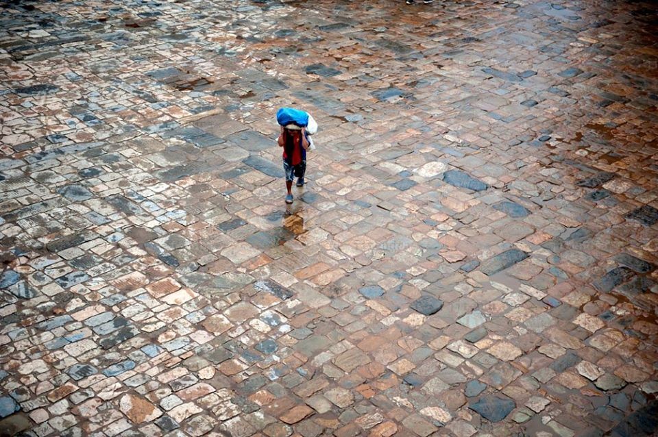 A porter walks passed by paved stone at Nyatapola Temple in Bhaktapur. 